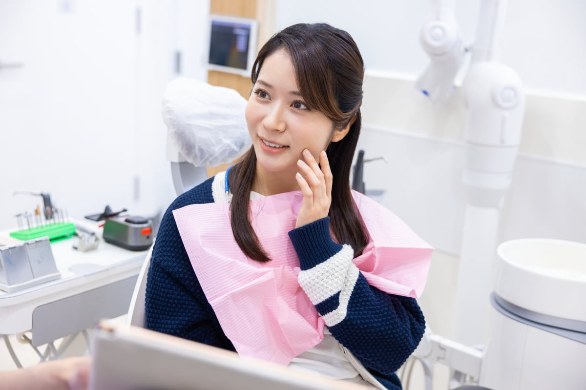 根管治療後の臭いが気になり歯科医院で相談をする女性
