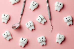 ピンク背景に顔が付いた沢山の歯と歯科用器具がある写真