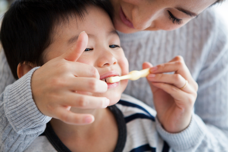母親に歯磨きをしてもらう男の子