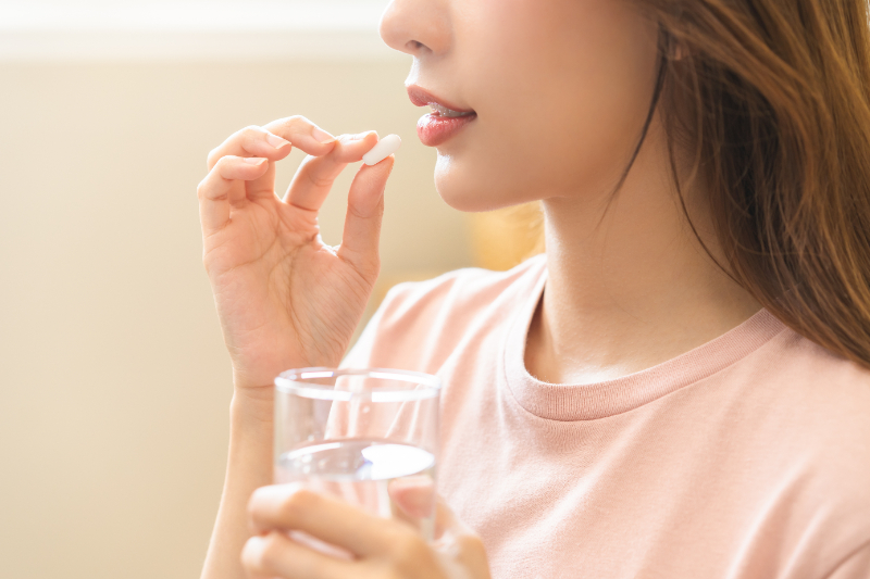 虫歯治療後に痛みがあり鎮痛剤を服用する女性