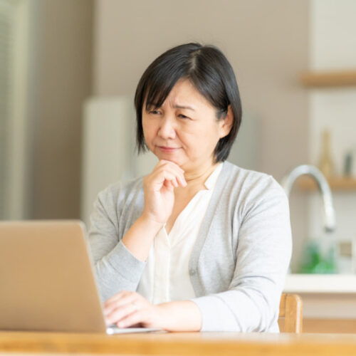 歯周病と糖尿病の関係についてパソコンで調べる女性