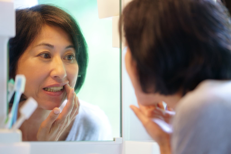 歯周病になった歯ぐきを鏡で見ている女性