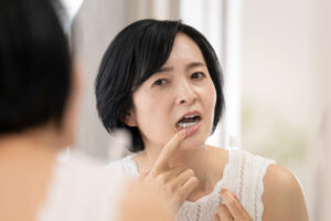 歯石が気になり鏡で確認する女性