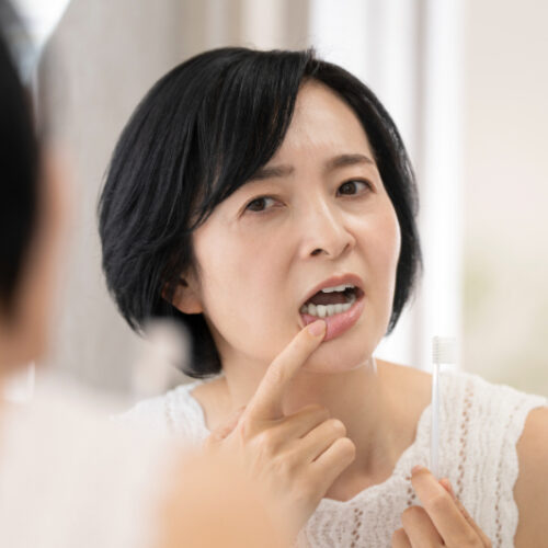 歯石が気になり鏡で確認する女性