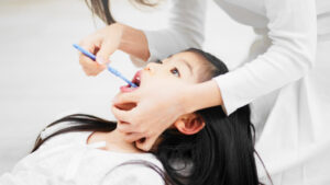 膝の上に頭をのせて仕上げ磨きをしてもらう子ども