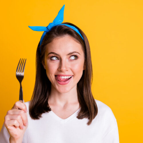 何を食べようかフォークを片手に考えている女性