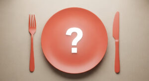 虫歯になりやすい食べ物は何かという疑問を示す皿の上のハテナマークとナイフとフォーク